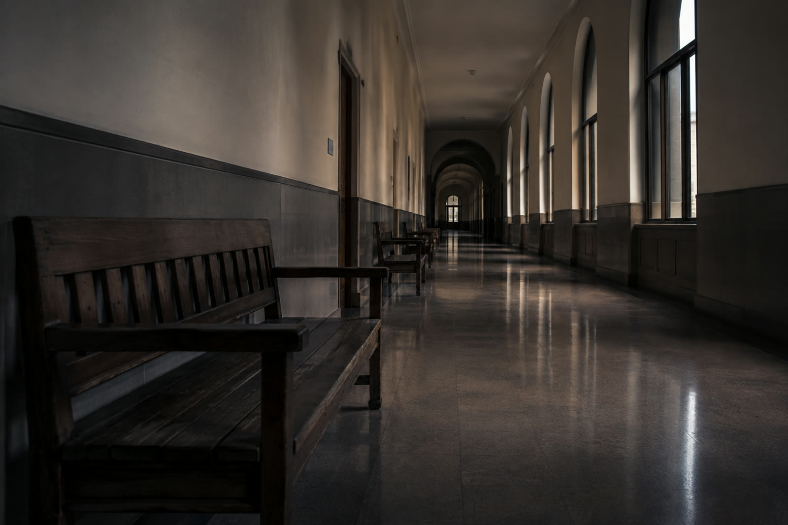 An empty courthouse corridor, benches along one wall and light from tall windows